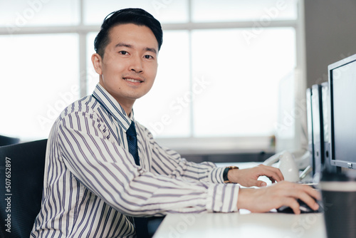 Obraz na plátně Asian male employee working on computer at desk in the office
