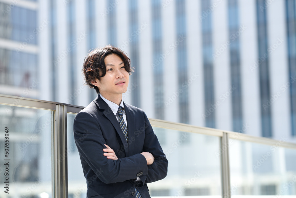 屋外で腕組みをするビジネスマンの男性 屋外で腕組みをするビジネスマンの男性