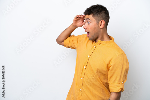 Young caucasian Brazilian man isolated on white background with surprise expression while looking side