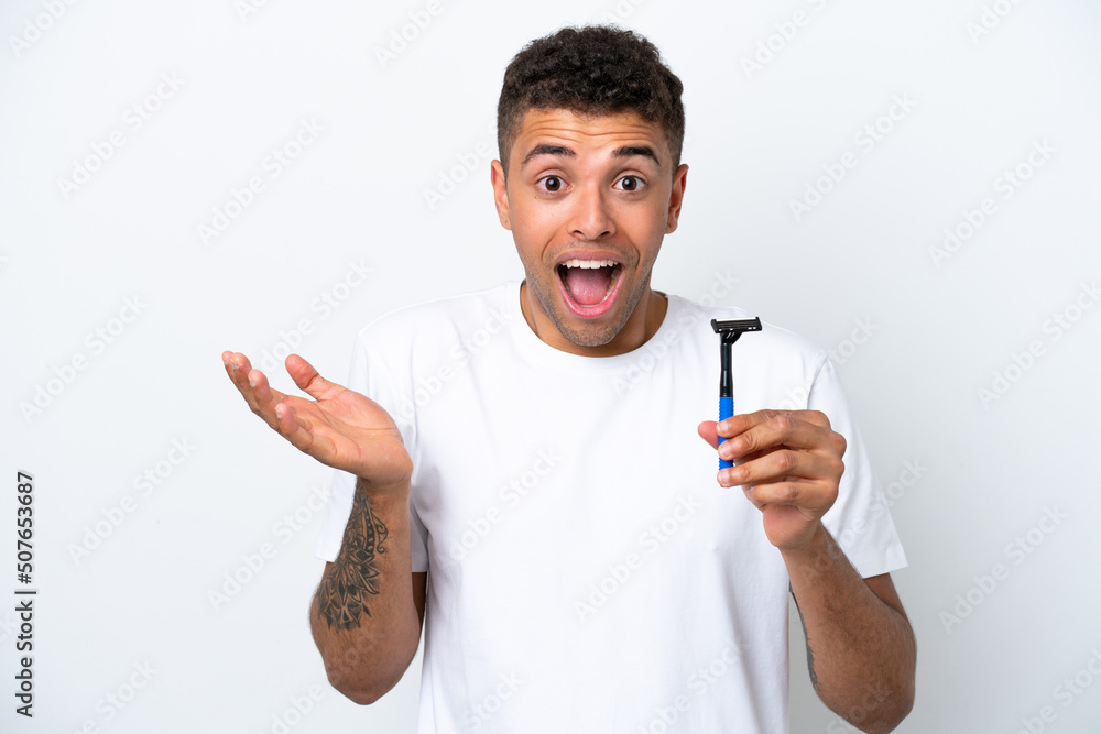Young Brazilian man shaving his beard isolated on white background with shocked facial expression Young Brazilian man shaving his beard isolated on white background with shocked facial expression