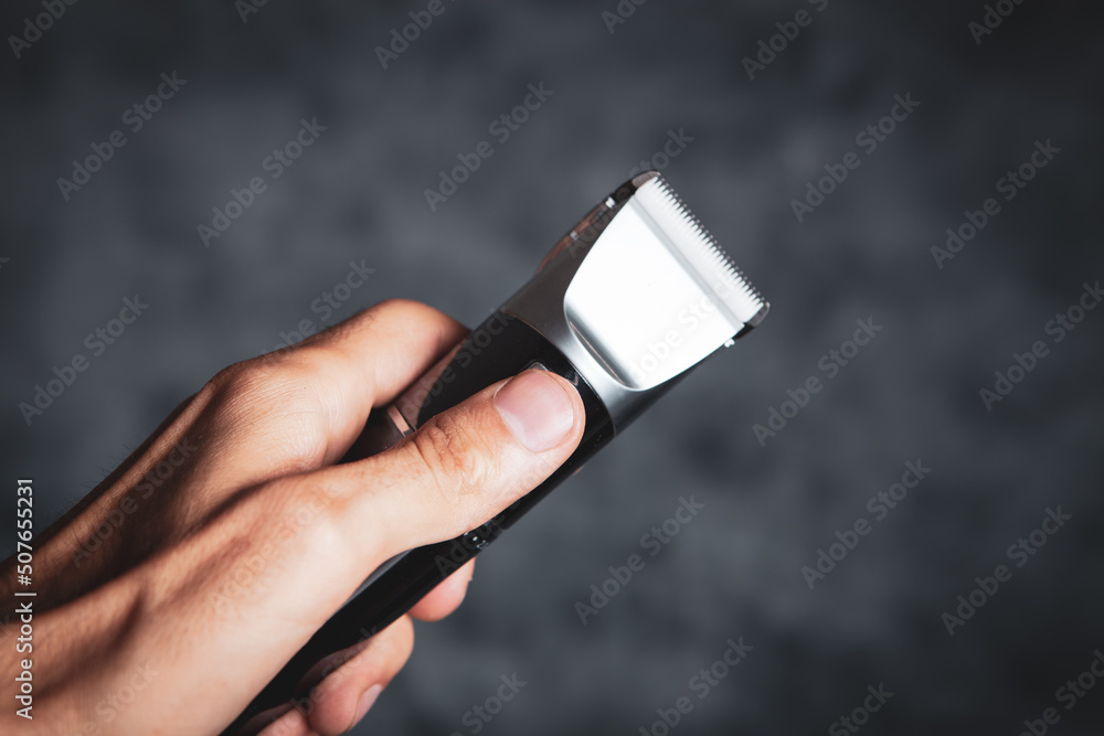 hand holding shaving machine on gray background hand holding shaving machine on gray background