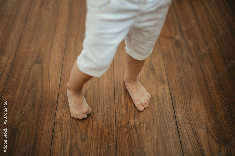 Barefoot  boy on wooden floor background.