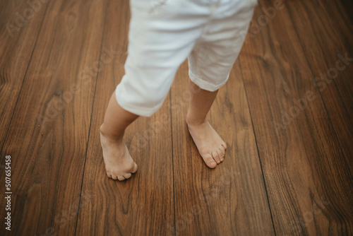 Barefoot  boy on wooden floor background.