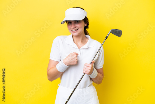 young caucasian woman playing golf isolated on yellow background with surprise facial expression