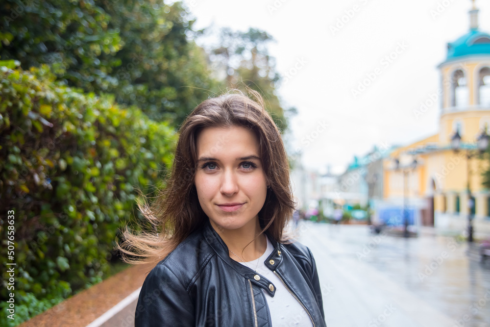 Beautiful young brunette girl in a black jacket on a city street against the background of an Orthodox Church. Moscow, Russia Beautiful young brunette girl in a black jacket on a city street against the background of an Orthodox Church. Moscow, Russia