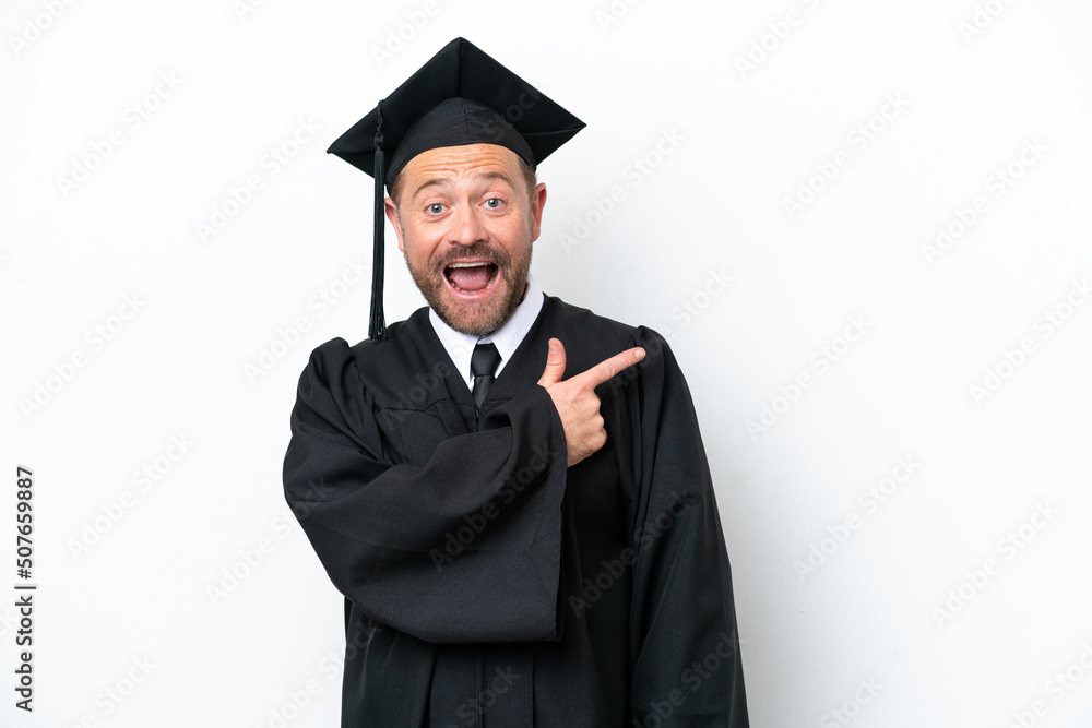 Middle age university graduate man isolated on white background surprised and pointing side Middle age university graduate man isolated on white background surprised and pointing side