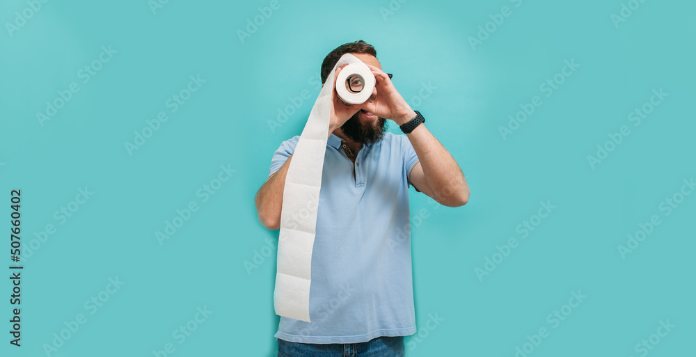 Man with happy face looks astonishingly through toilet paper roll. Funny promotion poster. Hygiene and sanitation. A man with a joyful face holds toilet paper. Man with happy face looks astonishingly through toilet paper roll. Funny promotion poster. Hygiene and sanitation. A man with a joyful face holds toilet paper.