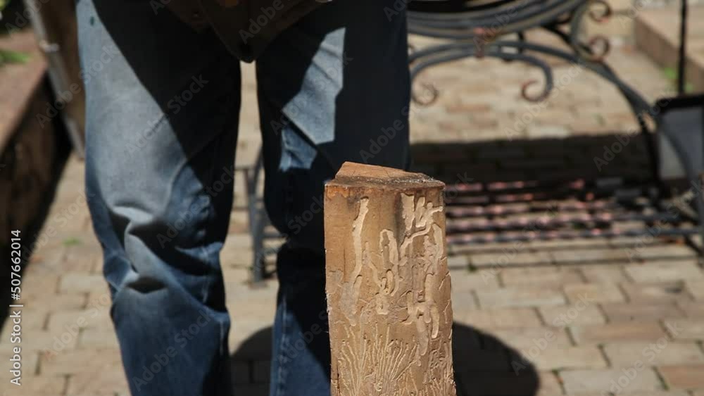 A man in jeans is chopping wood with an axe. Forged brazier in the background A man in jeans is chopping wood with an axe. Forged brazier in the background