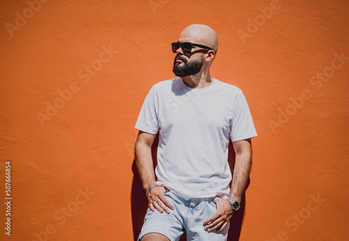 Male model with beard wearing white blank t-shirt on the background of an orange wall