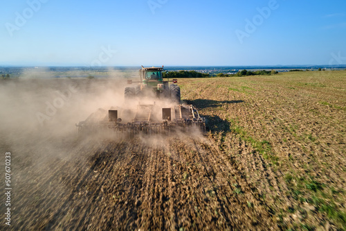 Aerial view of tractor plowing agriculural farm field preparing soil for seeding in summer © bilanol