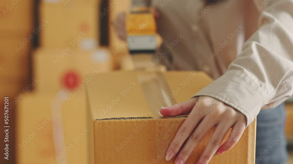 Asian woman working at online store warehouse packing product to parcel cardboard boxes, online e-commerce retail small business concept Asian woman working at online store warehouse packing product to parcel cardboard boxes, online e-commerce retail small business concept