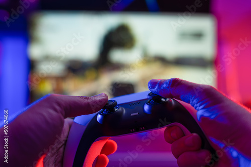 Close-up. Gamepad in the hands of a gamer on a technological background. Neon lighting. Video games on modern equipment, new digital technologies, cyberspace, cybersport.