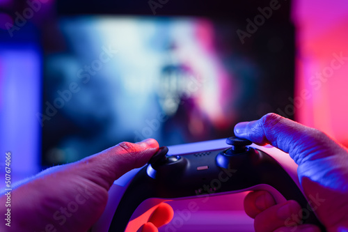 Close-up. A gamer holds a modern gamepad in his hands. Plays video games. Online communication with friends, video games, hobby, relaxation, recreation, game strategy.