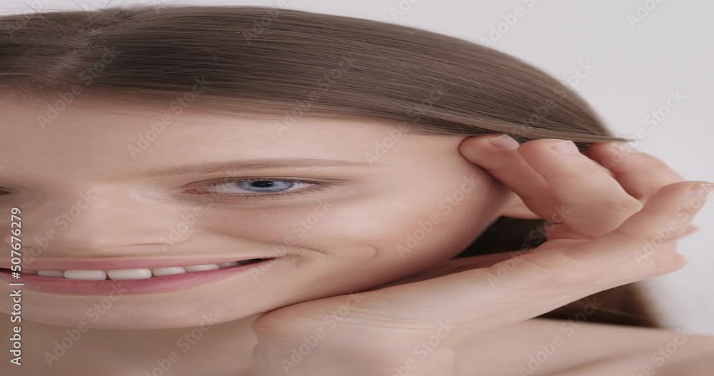 Face skin care. Stunning young woman gently massaging skin under blue eyes over grey studio background. Portrait of adorable female model with natural beauty. Face skin care. Stunning young woman gently massaging skin under blue eyes over grey studio background. Portrait of adorable female model with natural beauty.