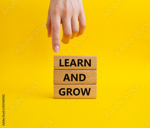 Learn and grow symbol. Concept words 'Learn and grow' on wooden blocks. Beautiful yellow background. Businessman hand. Business and Learn and grow concept. Copy space.