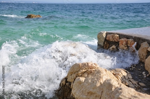 Sea, big wave and splash over the stones.Wave splashing on a Croatian beach on early summer. Waves splashing into white rocks on the coast of Rijeka beach Pecine. big wave and splash over the stone photo