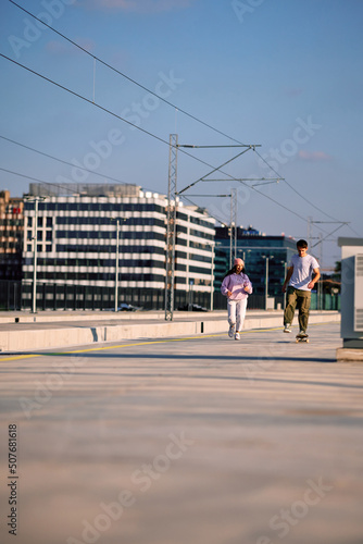 Two teenage friends skating and running on railroad station.