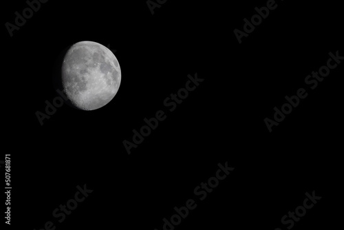 waxing moon in the second quarter in the night black sky with space for text on the left