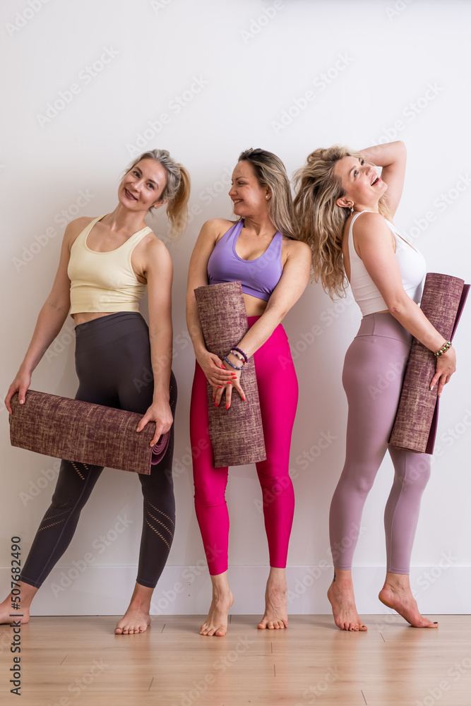 Fototapeta premium three young woman smiling talking holding yoga mat in sport wear in white studio, yoga teacher, workout