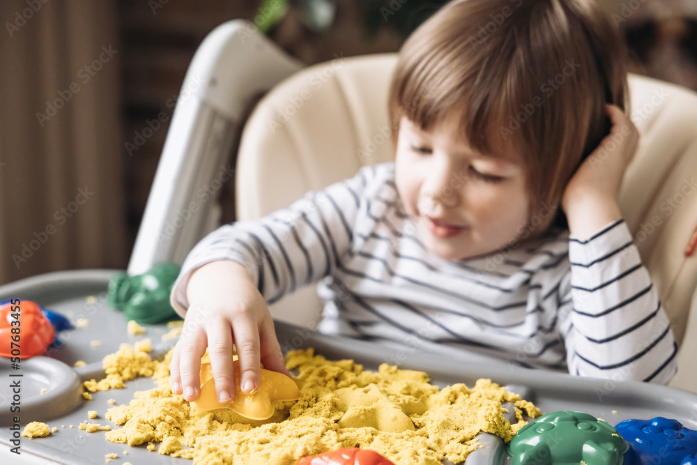 Cute little boy playing with kinetic sand. Development of fine motor skills. Early sensory education. Activities Montessori. Sensory plays at home. Cute little boy playing with kinetic sand. Development of fine motor skills. Early sensory education. Activities Montessori. Sensory plays at home.