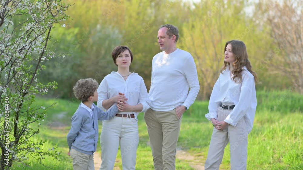 Happy family outdoors. Happy smiling family walks on a green park on a sunny day. Mother, father and children having fun on spring day. Happy family outdoors. Happy smiling family walks on a green park on a sunny day. Mother, father and children having fun on spring day.