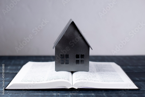 Open Bible. Miniature house. Prayer. On a wooden table. Holy book, Scripture.