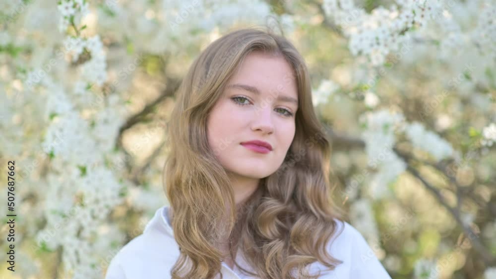 Portrait of a cute young girl in a beautiful blooming garden. Happy beautiful girl in garden with blooming trees. Beauty model girl face. Portrait of a cute young girl in a beautiful blooming garden. Happy beautiful girl in garden with blooming trees. Beauty model girl face.