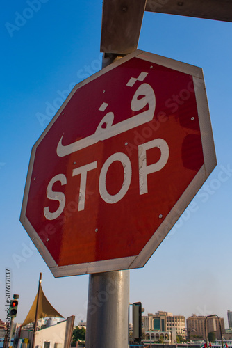 Dubai, road sign with STOP text in Arabic language seen from below over the city