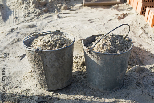 Close-up of two dirty construction buckets with sand on a construction site. © 22_monkeyzzz