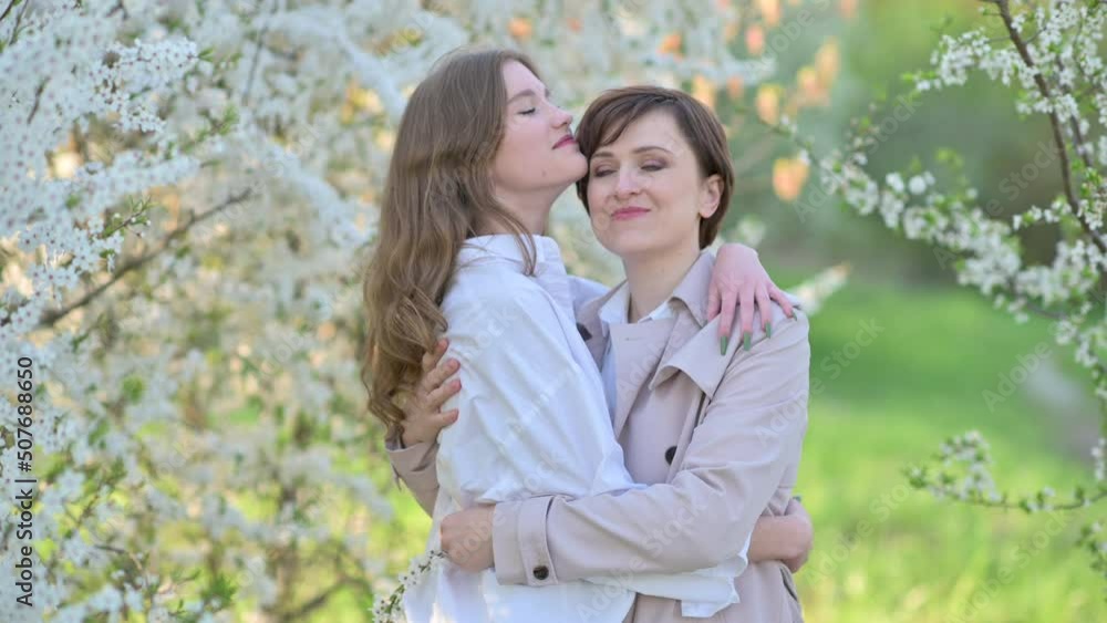 Happy family. Loving tender mum hugging with a cute daughter in a blooming garden. Mommy and Kid outdoor together. Happy family. Loving tender mum hugging with a cute daughter in a blooming garden. Mommy and Kid outdoor together.