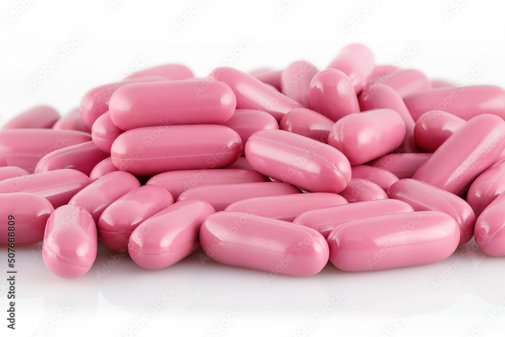 Pink capsules with medical drugs or supplements isolated on white background, top view.