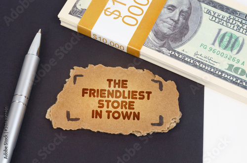 On the table are dollars, a pen and a cardboard sign with the inscription - the friendliest store in town photo