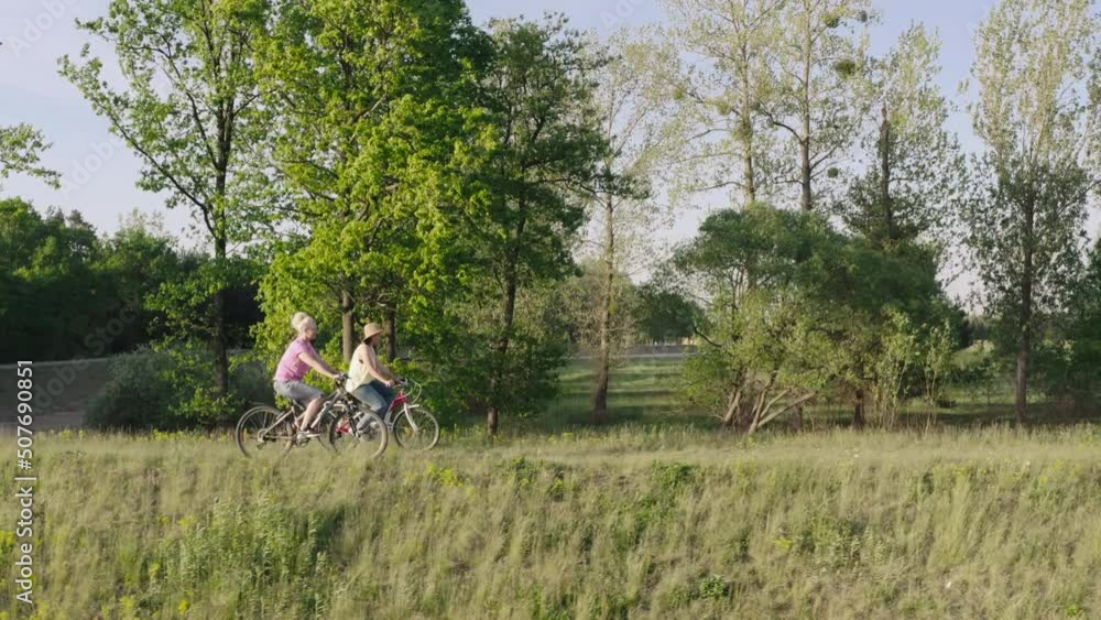 Mother and daughter ride bicycles in the woods. Girlfriends spend time together in nature riding bicycles in the park. Mother and daughter ride bicycles in the woods. Girlfriends spend time together in nature riding bicycles in the park.