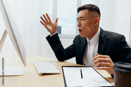 businessmen in a suit glass of coffee sits at a tablein front of a computer Workspace photo