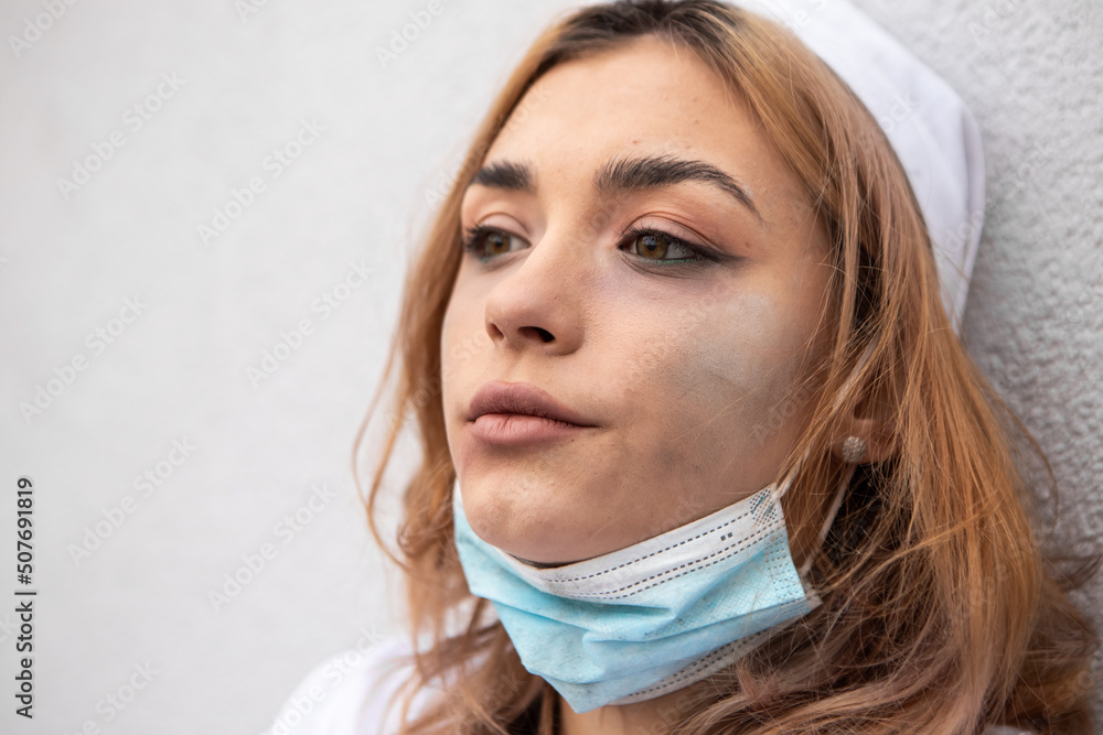 Dirty tired exhausted nurse with ash on face sitting outside hospital infirmary after hard working day or surgery. Doctor woman dressed white medical gown, face mask have a rest due to stress
Dirty tired exhausted nurse with ash on face sitting outside hospital infirmary after hard working day or surgery. Doctor woman dressed white medical gown, face mask have a rest due to stress