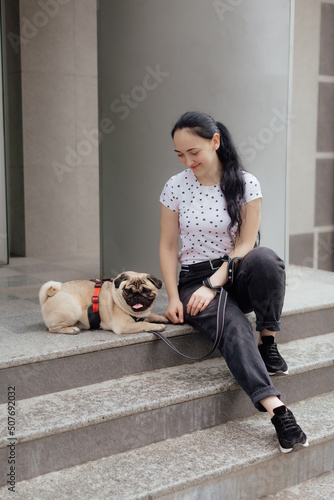 Young girl goes for walk with doggy pug in park. Selective focus. © pugovica_88