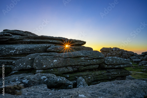 Sunburst through a granite tor, Dartmoor National Park, Devon, England, UK photo