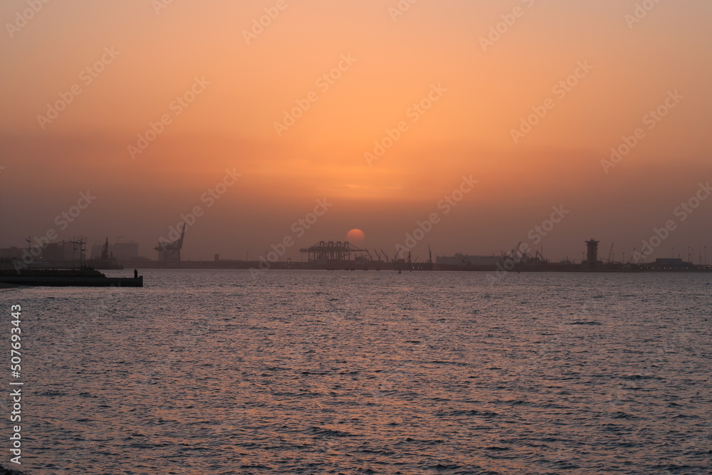 sunset over sea port with ships