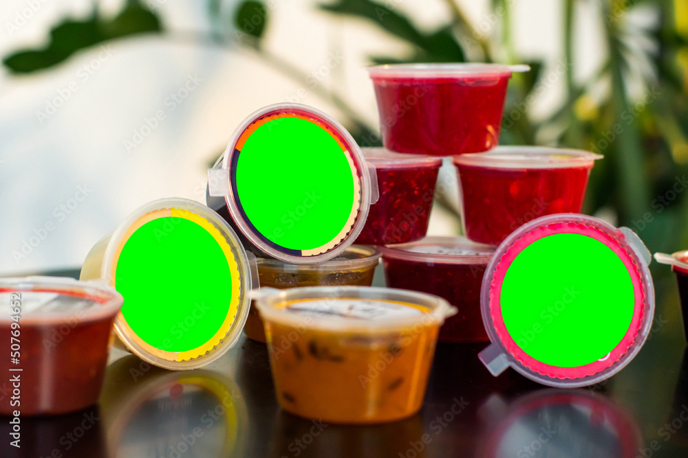 On the table are small containers with jam of different types and ...