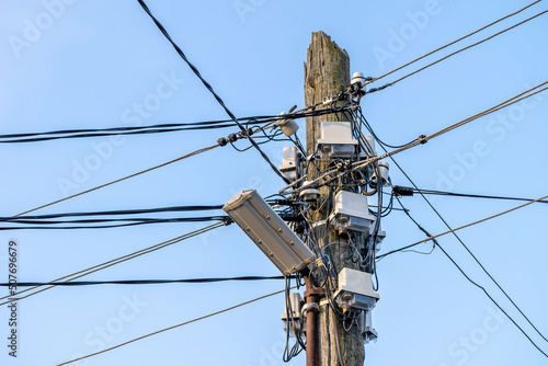 The upper part of an old pole with a lot of fixed wires and power transmission devices.