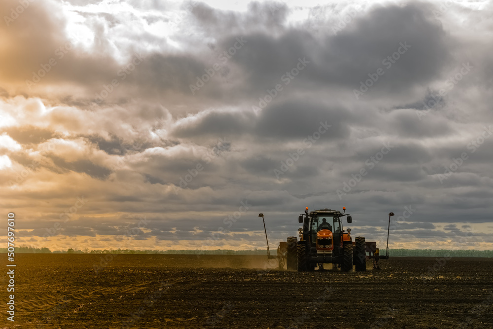 Fototapeta premium A tractor with a seed drill is engaged in planting corn. Agricultural industry development concept.