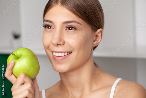 Beautiful woman with healthy white teeth holding green apple