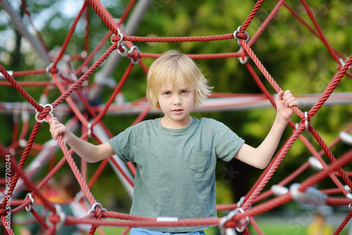 Cute preschooler boy having fun on outdoor playground. Spring summer autumn active sport leisure for kids. Activity for family with children. Equipment of entertainment. © Maria Sbytova