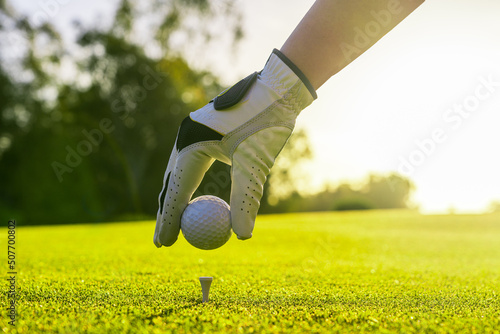 Closeup of golfer wearing glove placing golf ball on a tee at golf course