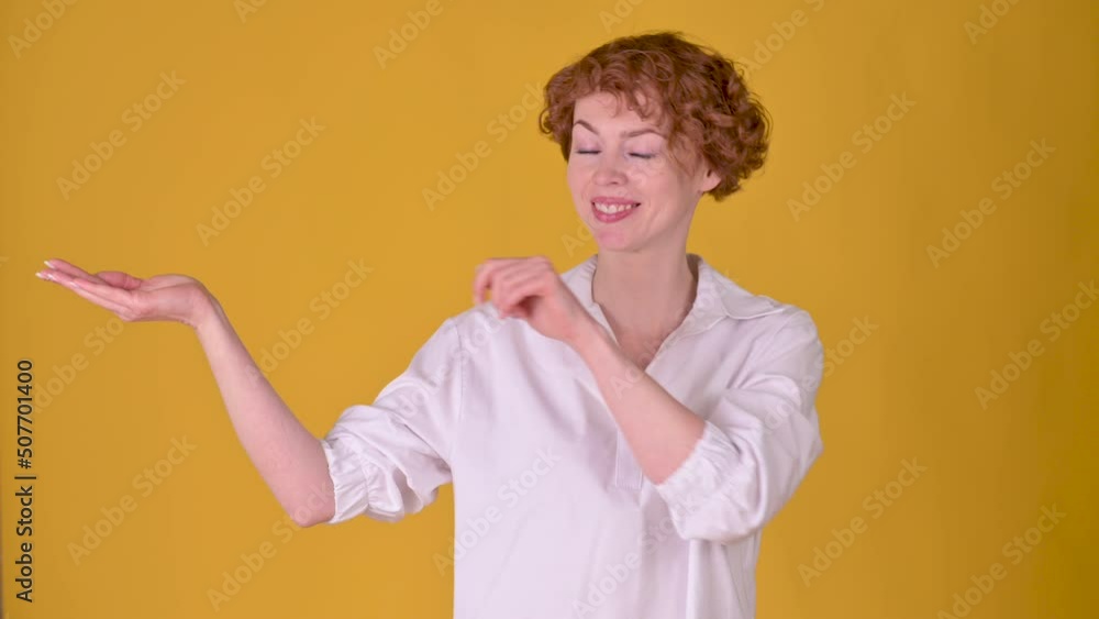 Young cheerful girl with red hair pointing empty place on her palm and smiling at the camera. Attractive woman showing empty space for commercial image. People lifestyle Young cheerful girl with red hair pointing empty place on her palm and smiling at the camera. Attractive woman showing empty space for commercial image. People lifestyle
