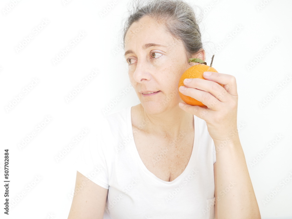 Forty nine year old woman in a white T-Shirt against a white background with an orange Forty nine year old woman in a white T-Shirt against a white background with an orange