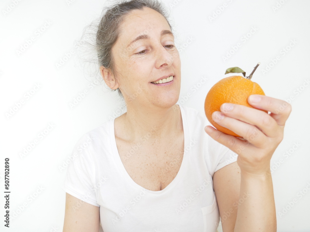 Forty nine year old woman in a white T-Shirt against a white background with an orange Forty nine year old woman in a white T-Shirt against a white background with an orange