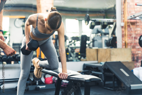 Fit woman exercising with dumbbell weights on the bench at the gym. High quality photo