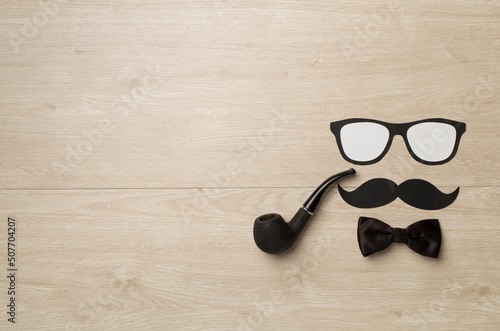 Glasses, mustache and bow tie on wooden background, top view. Happy Father's Day concept