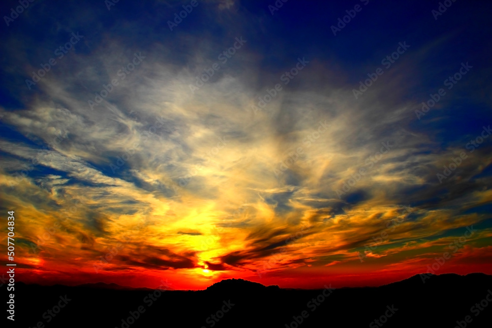 Interesting scene with a background full of filamentous clouds and alternating cold and warm colours of the sky standing above the dark stark silhouette of some hills in Marche region Interesting scene with a background full of filamentous clouds and alternating cold and warm colours of the sky standing above the dark stark silhouette of some hills in Marche region